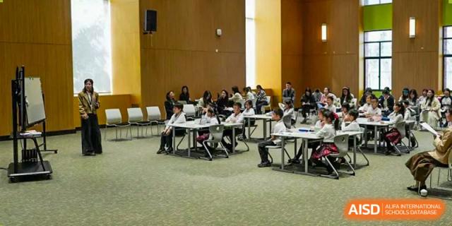 A group of students sitting at a table in a classroom or a meeting room. Hangzhou Dipont School of Arts and Science.