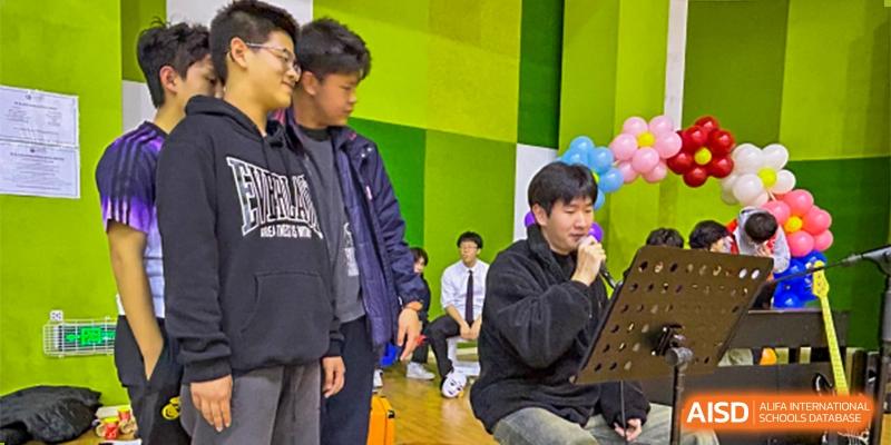 Students are gathered in a brightly colored room, one seated and looking at a device. Hangzhou Dipont School of Arts and Science.