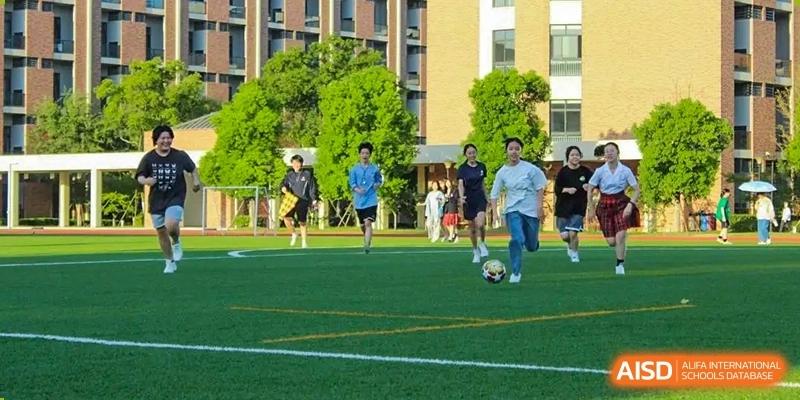 Students are playing soccer on a grassy field. Hangzhou Dipont School of Arts and Science.