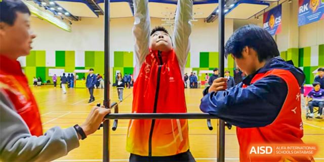A male student is lifting weights in the school gymnasium. Hangzhou Dipont School of Arts and Science.