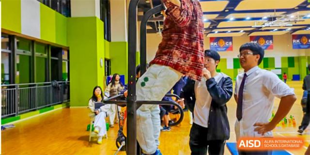 A student is doing pull-ups in a gym. Hangzhou Dipont School of Arts and Science.