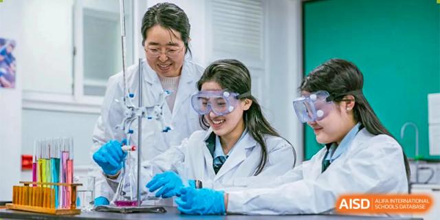 Two students from Ningbo Huamao International School working together on a science experiment, with a teacher supervising.