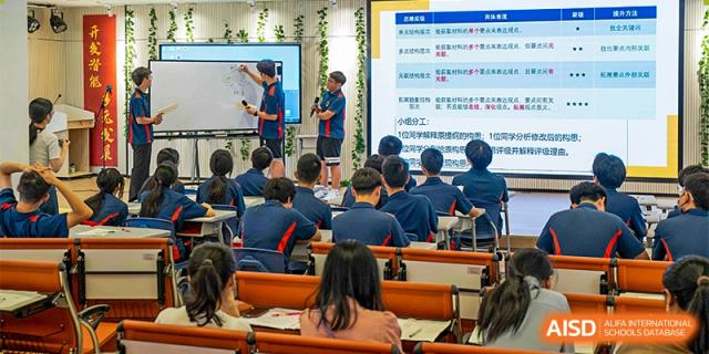 A teacher from Ningbo Huamao International School writing on an interactive whiteboard while students watch from their desks.
