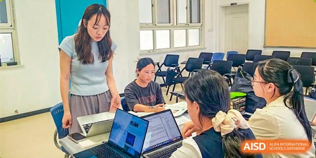 Students and a teacher from Ningbo Huamao International School collaborating on a project with a laptop.