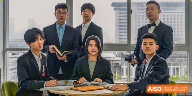 Three students from Ningbo Huamao International School dressed in blazers, posing in a classroom.