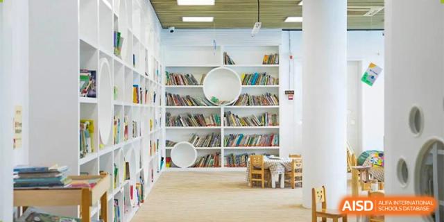 A close-up of a corner of the Ningbo Huamao International School library, showing a bookshelf and a small chair.