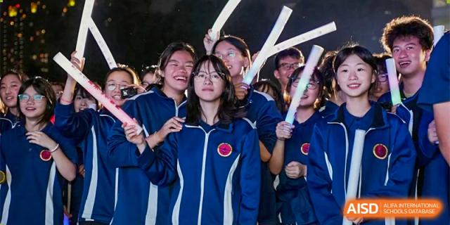 Students from Ningbo Huamao International School cheering and holding light-up batons.