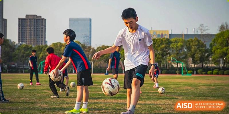 Ningbo Huamao International School students playing a game of soccer on a field.