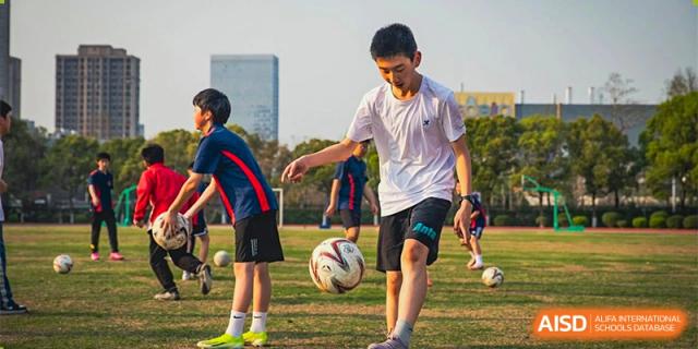 Ningbo Huamao International School students playing a game of soccer on a field.