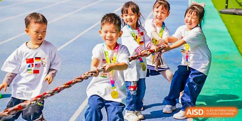 Ningbo Huamao International School students smiling and holding a rope during a fun outdoor activity.