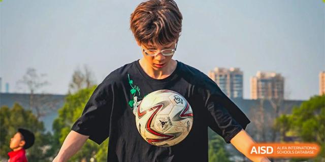 A close-up of a student from Ningbo Huamao International School wearing a black shirt and holding a soccer ball.