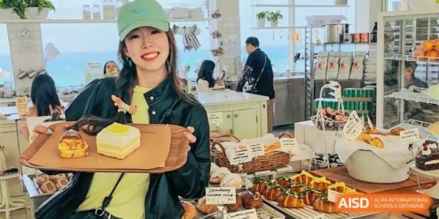 A staff member or student from Ningbo Huamao International School smiling behind a counter with various food items.