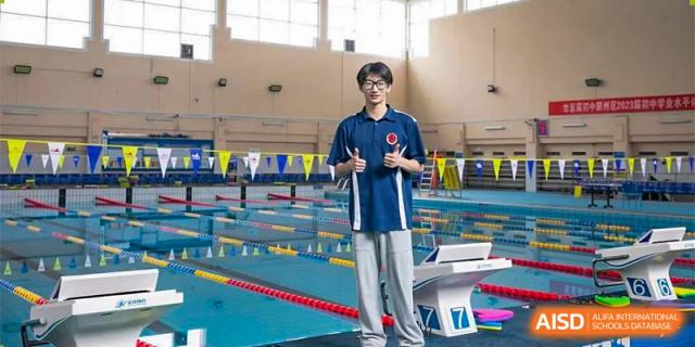 A student from Ningbo Huamao International School standing by a swimming pool, ready to swim.