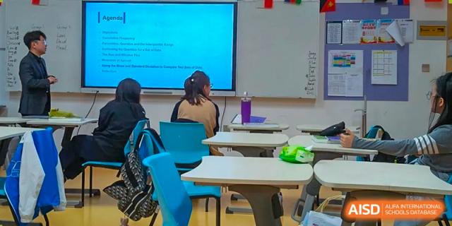 Qingdao MINGDE School students watching a presentation on a screen in a classroom.