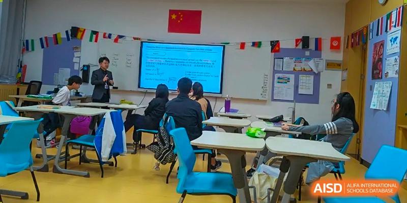 Qingdao MINGDE School students seated at desks in a classroom with a presentation on the screen.