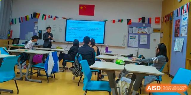 Qingdao MINGDE School students seated at desks in a classroom with a presentation on the screen.