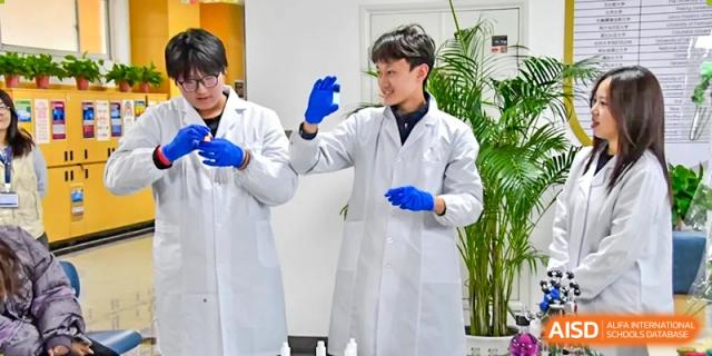 A Qingdao MINGDE School student in a lab coat showing off a test tube during an experiment.