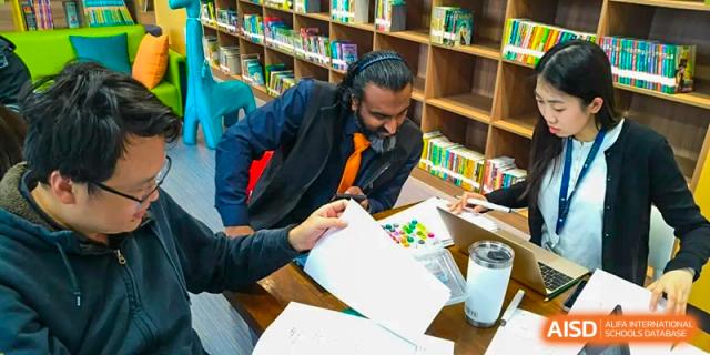 Qingdao MINGDE School students working on a project with notebooks and materials.
