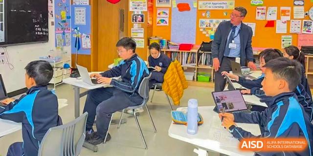 A young Qingdao MINGDE School student seated at a desk in a classroom.