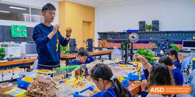 Qingdao MINGDE School students building with colorful blocks in a classroom.