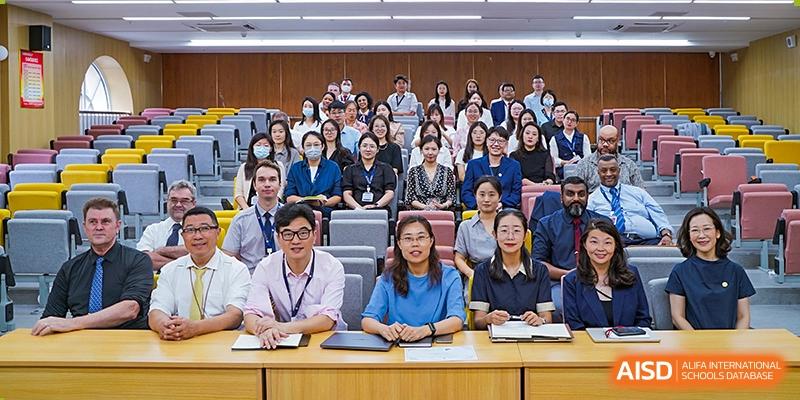 A group of teachers and staff from Qingdao MINGDE School posing for a photo in a lecture hall.