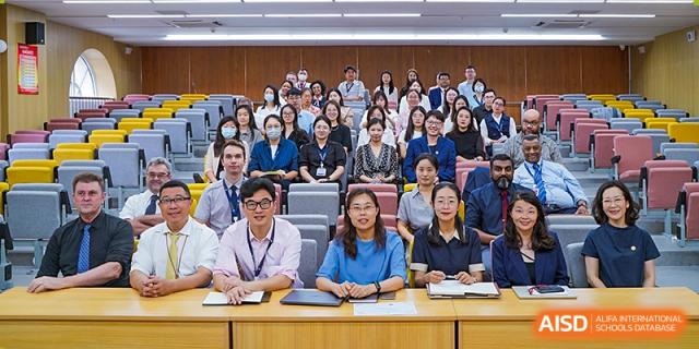 A group of teachers and staff from Qingdao MINGDE School posing for a photo in a lecture hall.