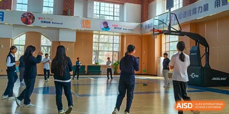 Qingdao MINGDE School students playing basketball in the school gymnasium.