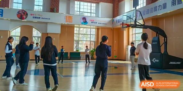 Qingdao MINGDE School students playing basketball in the school gymnasium.