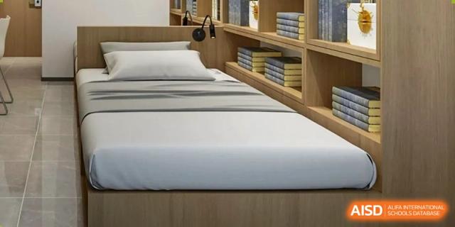 A dormitory room at Qingdao MINGDE School with a bed and a built-in bookshelf.