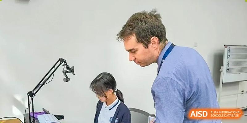 A Qingdao MINGDE School teacher helping a student in a classroom.