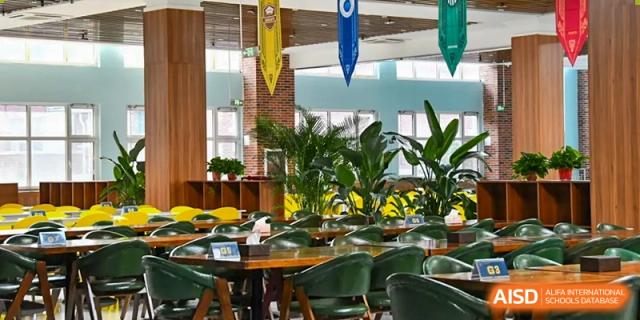The indoor cafeteria or lounge area at Qingdao MINGDE School with plants and modern furniture.