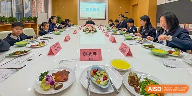 Qingdao MINGDE School students and staff seated around a large table during a meal.