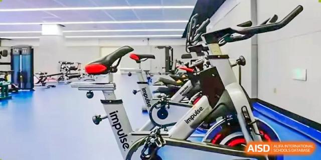 Exercise bikes and other fitness equipment inside the gym at Qingdao MINGDE School.