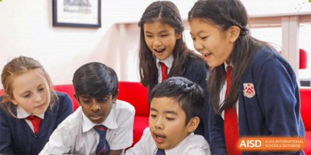 A group of students from Dulwich College Shanghai Pudong gathered around a table, looking at something.