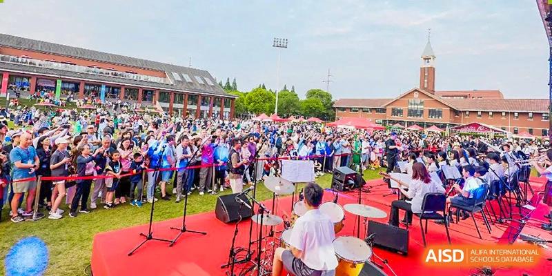 Students from Dulwich College Shanghai Pudong playing music on a stage with drums and other instruments.