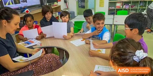 Students work together on a project at a large table in a classroom at Qingdao No.1 International School of Shandong Province (QISS).