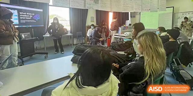A female student in a white coat looks at a project with other students in a classroom at Qingdao No.1 International School of Shandong Province (QISS).