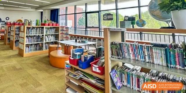 A bookshelf and books are visible in the school library or reading corner at Qingdao No.1 International School of Shandong Province (QISS).