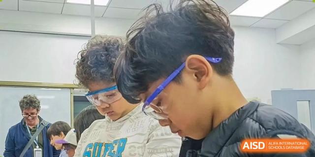 A student with glasses leans over to look at his work in a classroom at Qingdao No.1 International School of Shandong Province (QISS).
