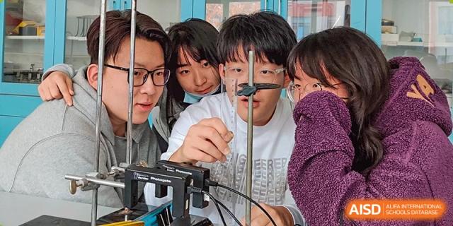 A group of students looks at a science experiment or project in a lab at Qingdao No.1 International School of Shandong Province (QISS).