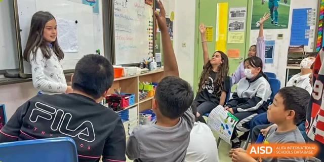 A student holds his hand up to answer a question in a classroom at Qingdao No.1 International School of Shandong Province (QISS).
