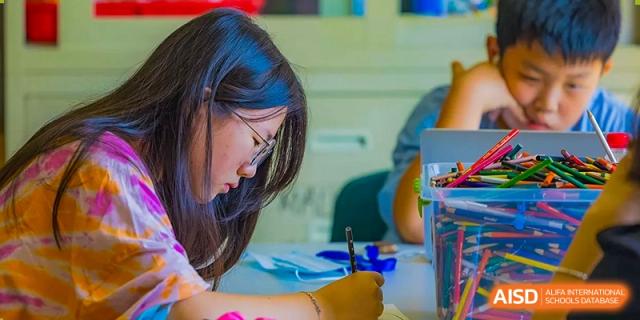 A female student with a ponytail looks at her work in a classroom at Qingdao No.1 International School of Shandong Province (QISS).