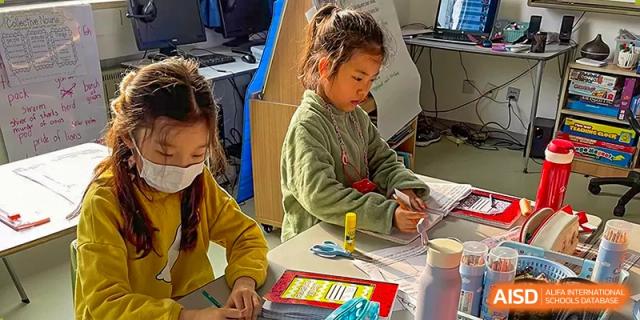 A young student works on a project at a desk in a classroom at Qingdao No.1 International School of Shandong Province (QISS).