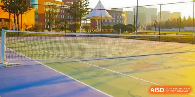 A tennis court and a running track outside a school building at Qingdao No.1 International School of Shandong Province (QISS).