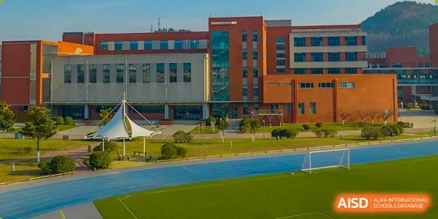A modern school building and a blue running track on the campus of Qingdao No.1 International School of Shandong Province (QISS).