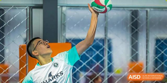 A male student raises a volleyball to serve during practice at Qingdao No.1 International School of Shandong Province (QISS).