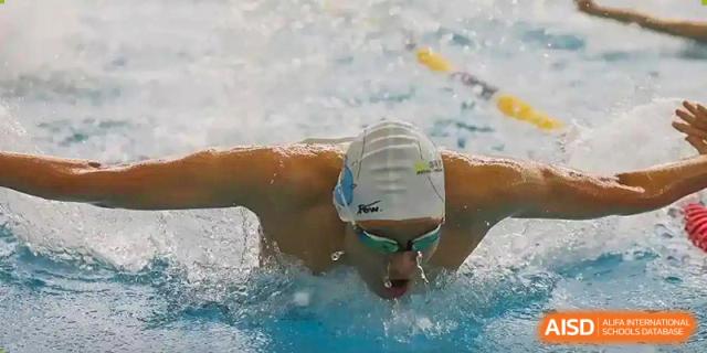 A student with a swim cap and goggles swims butterfly stroke in a pool at Qingdao No.1 International School of Shandong Province (QISS).