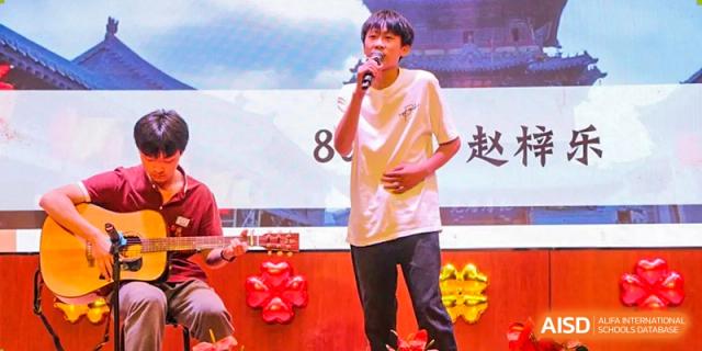 A male student singing into a microphone on stage during a performance or event at Yichang Tianwen International School.