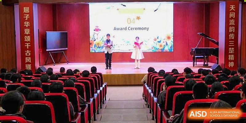Students standing on a brightly lit stage during an "Award Ceremony" in a school auditorium at Yichang Tianwen International School.