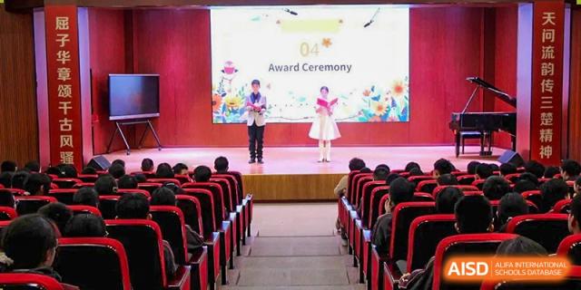 Students standing on a brightly lit stage during an "Award Ceremony" in a school auditorium at Yichang Tianwen International School.